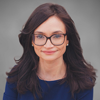 Woman in blue sitting against gray background